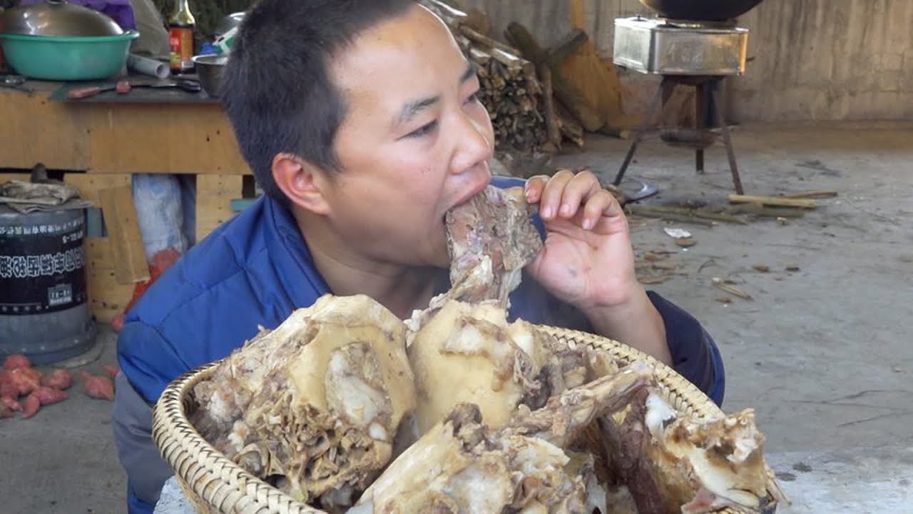 阿哥把熏腊猪头剩下的猪头骨炖了一大锅，出锅后忍不住先吃了一块