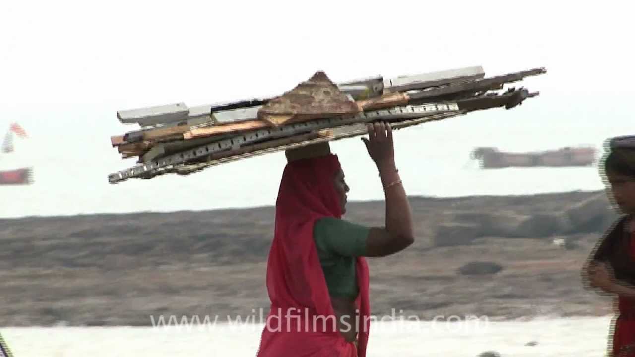 Woman carries away parts of dead ships, at Alang ship recycling yard