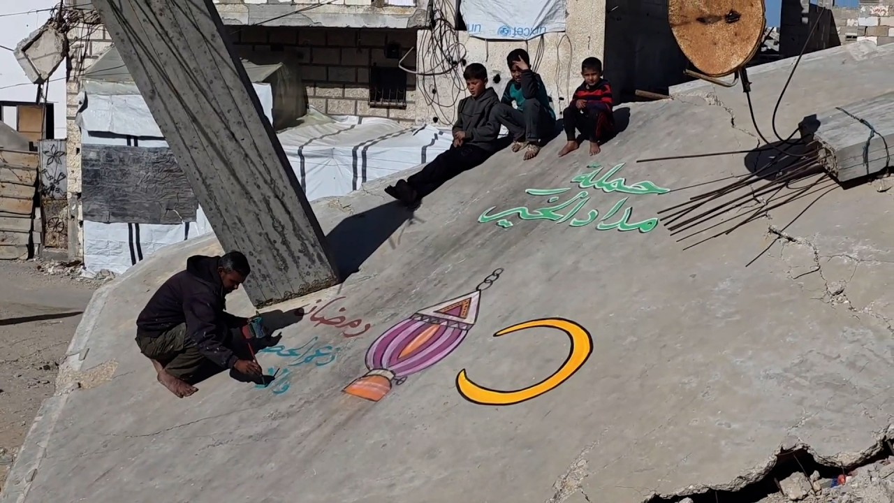 هاني دهمان يرسم على أنقاض المنازل والأحياء المدمرة في خان يونس جنوب غزة احتفالاَ بشهر رمضان