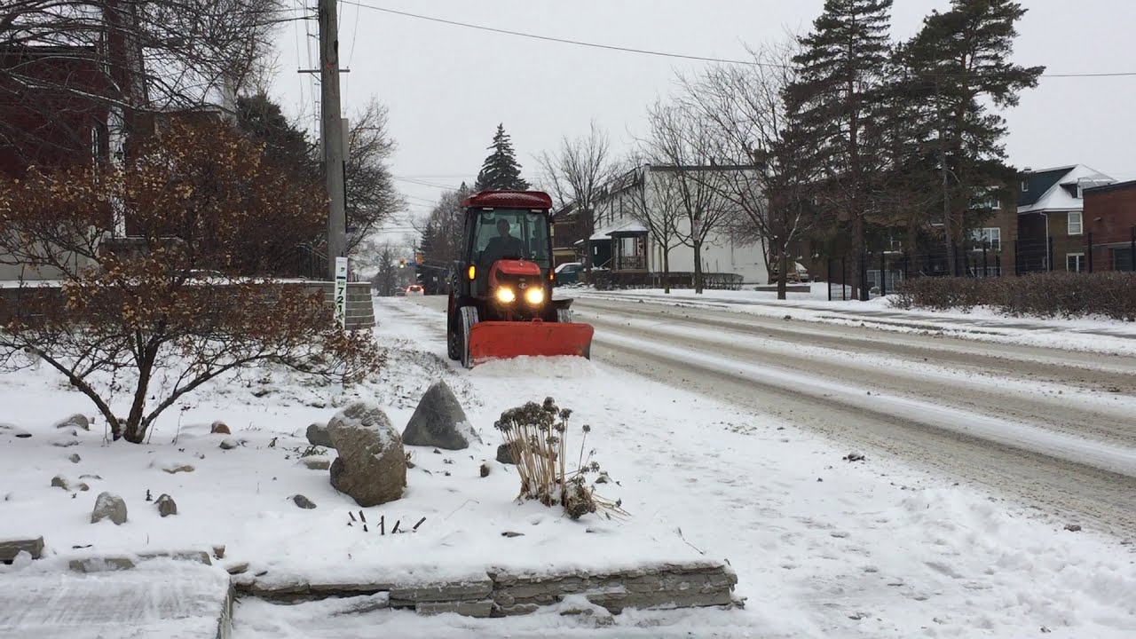 City Of Ottawa Kubota Sidewalk Plow Plowing A Sidewalk After A Storm.