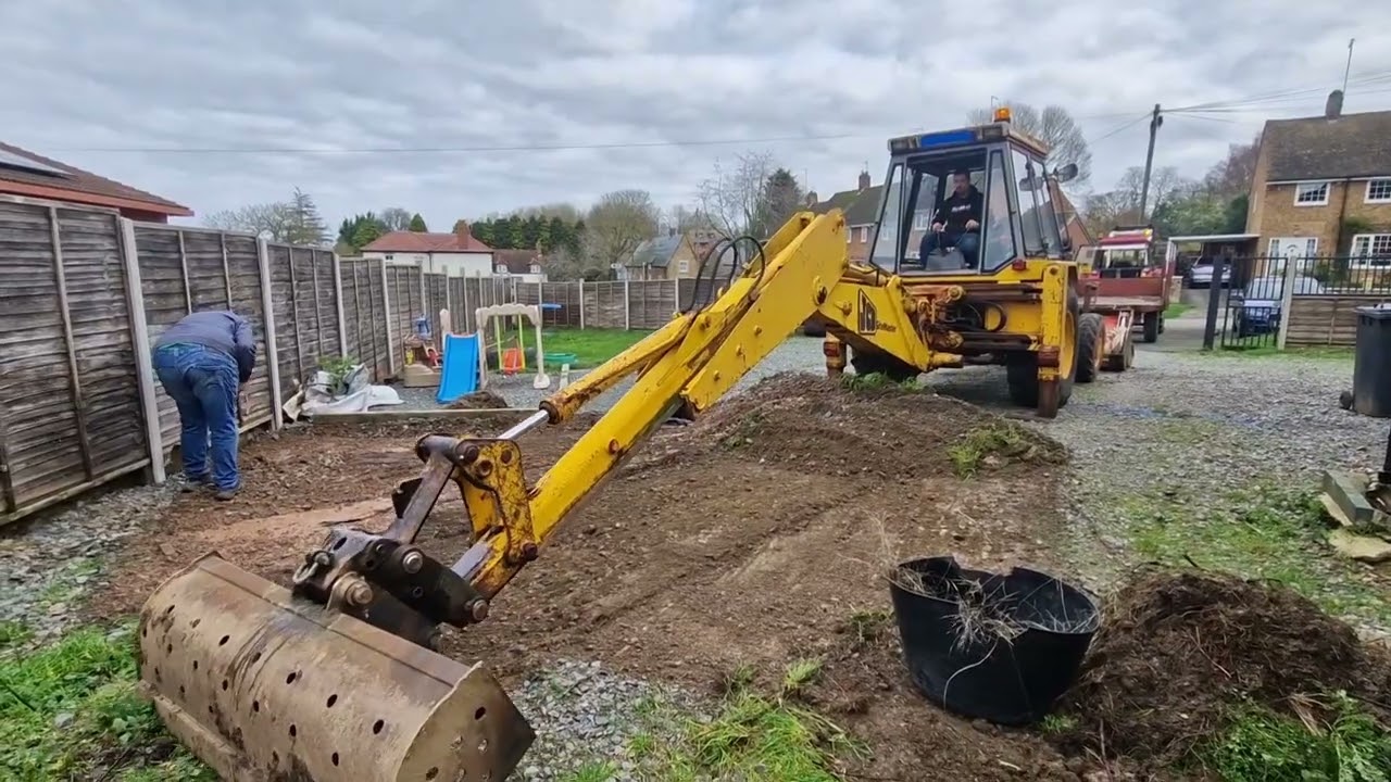 Jcb 3cx gray cab taking stone off a driveway 
