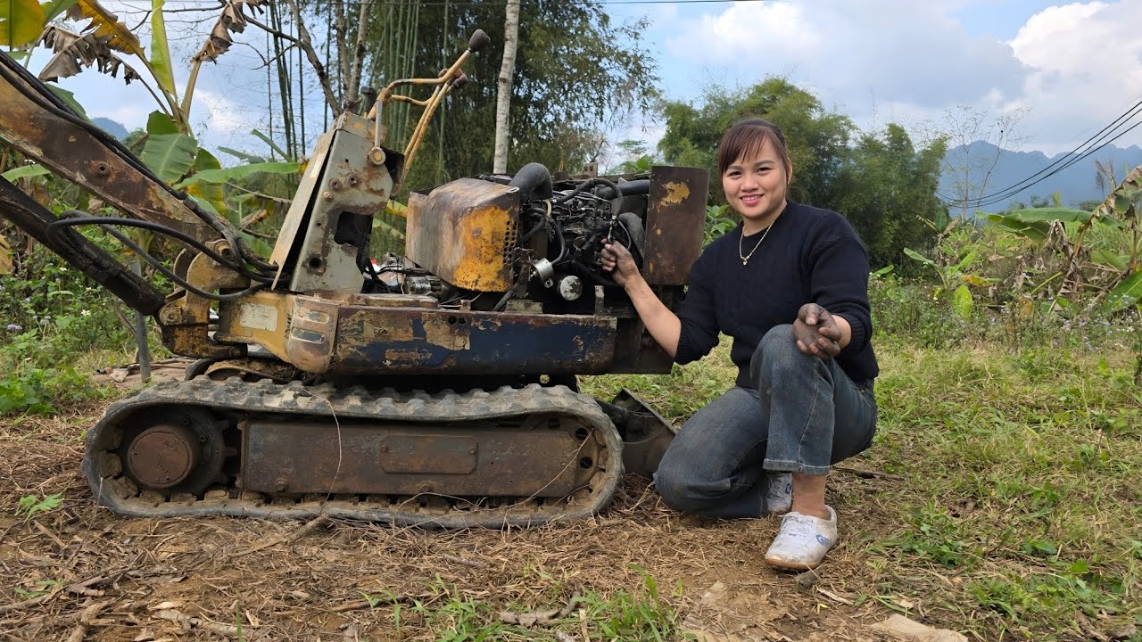 Girl repairs and restores excavator with broken engine and rust.