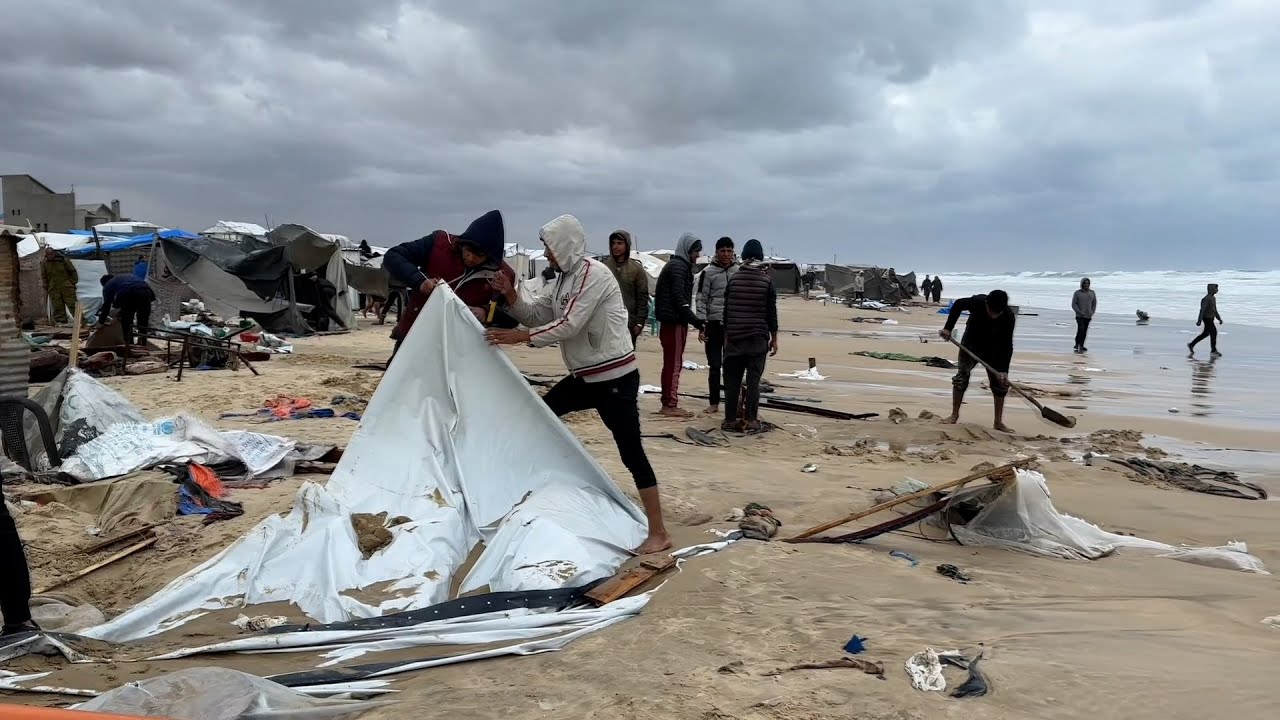 نازحون يحاولون إصلاح خيامهم بعد غرقها بمياه البحر بسبب ارتفاع المدّ على طول شاطئ خان يونس جنوب غزة