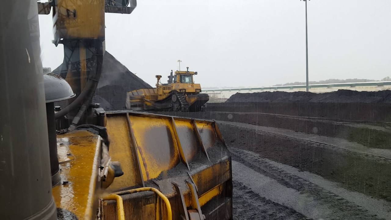 Caterpillar D10T Coal Dozer Pushes to feeder in snow and rain