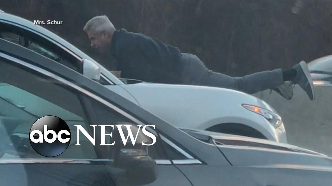 Video shows man hanging from a car hood on the highway