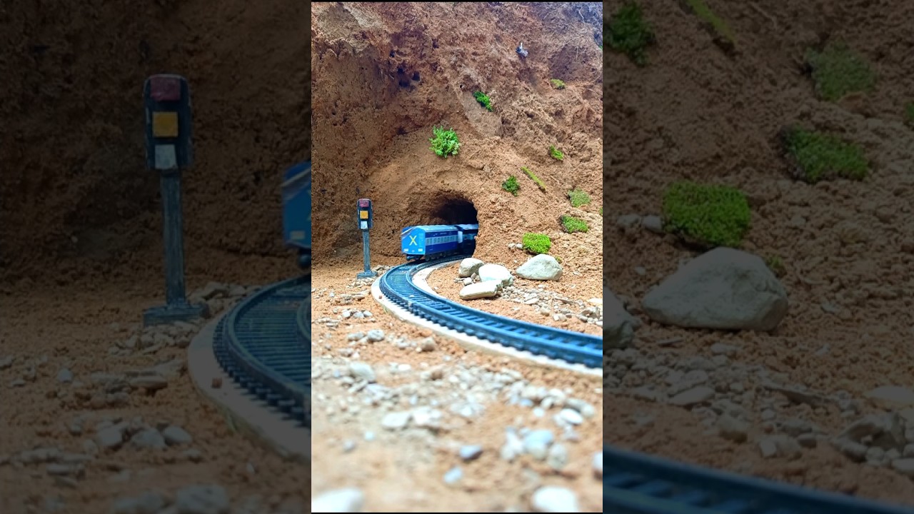Blue Train Enters Tunnel Through Rocky Hillside with Stones on Track
