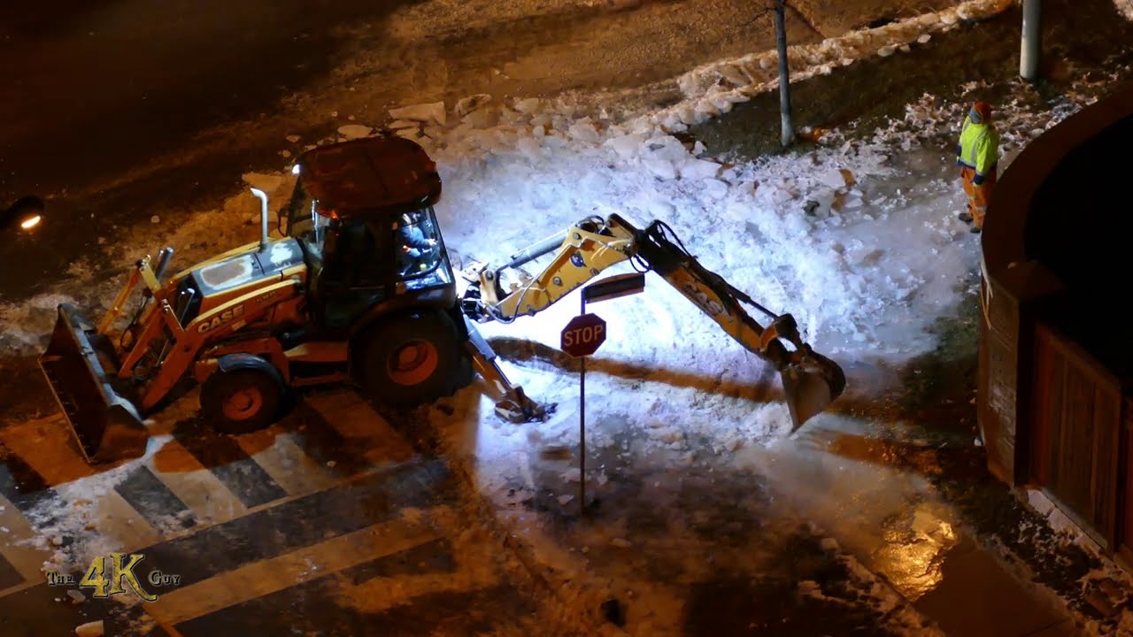 Case 580 loader breaking and plowing thick frozen ice buildup over manhole