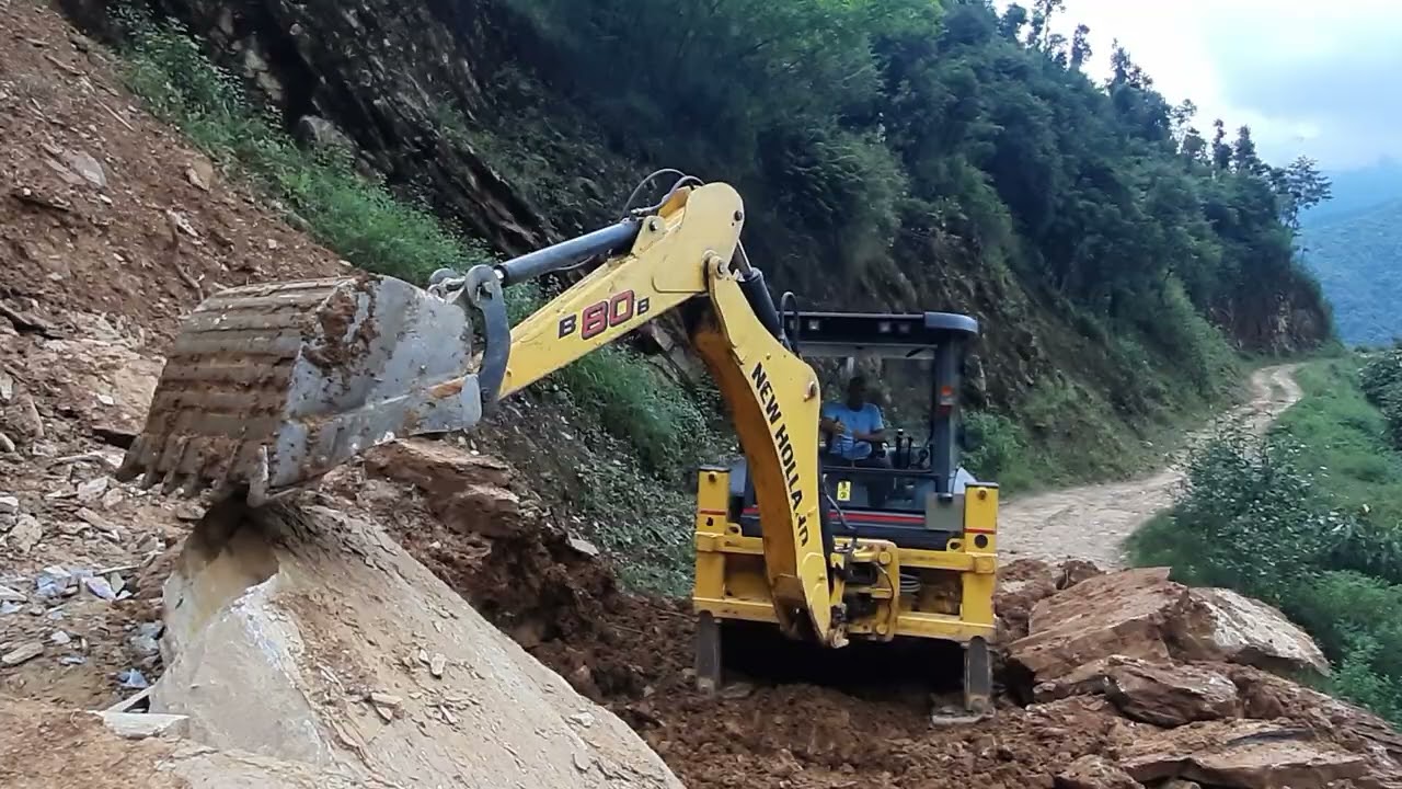 Outstanding struggle-jcb backhoe struggling with heavy rocks on clearing piledup monsoon landslide