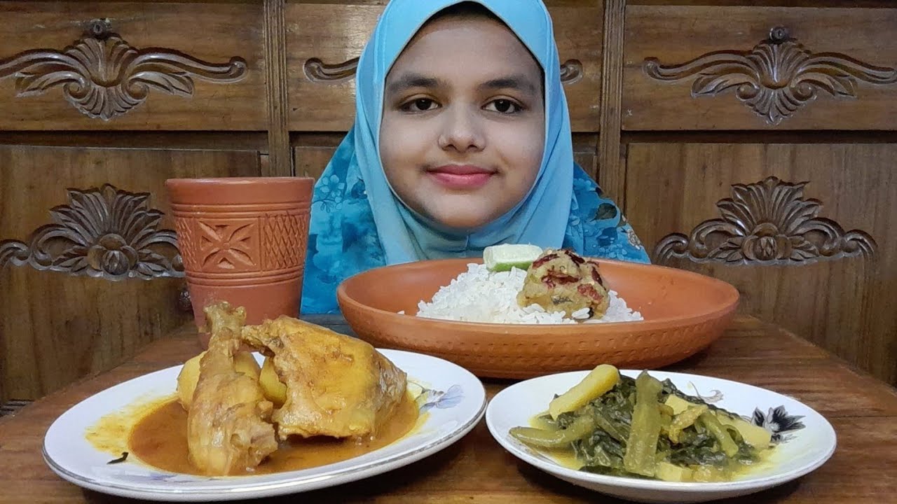 eating chicken curry, aloo borta, pui shak with rice