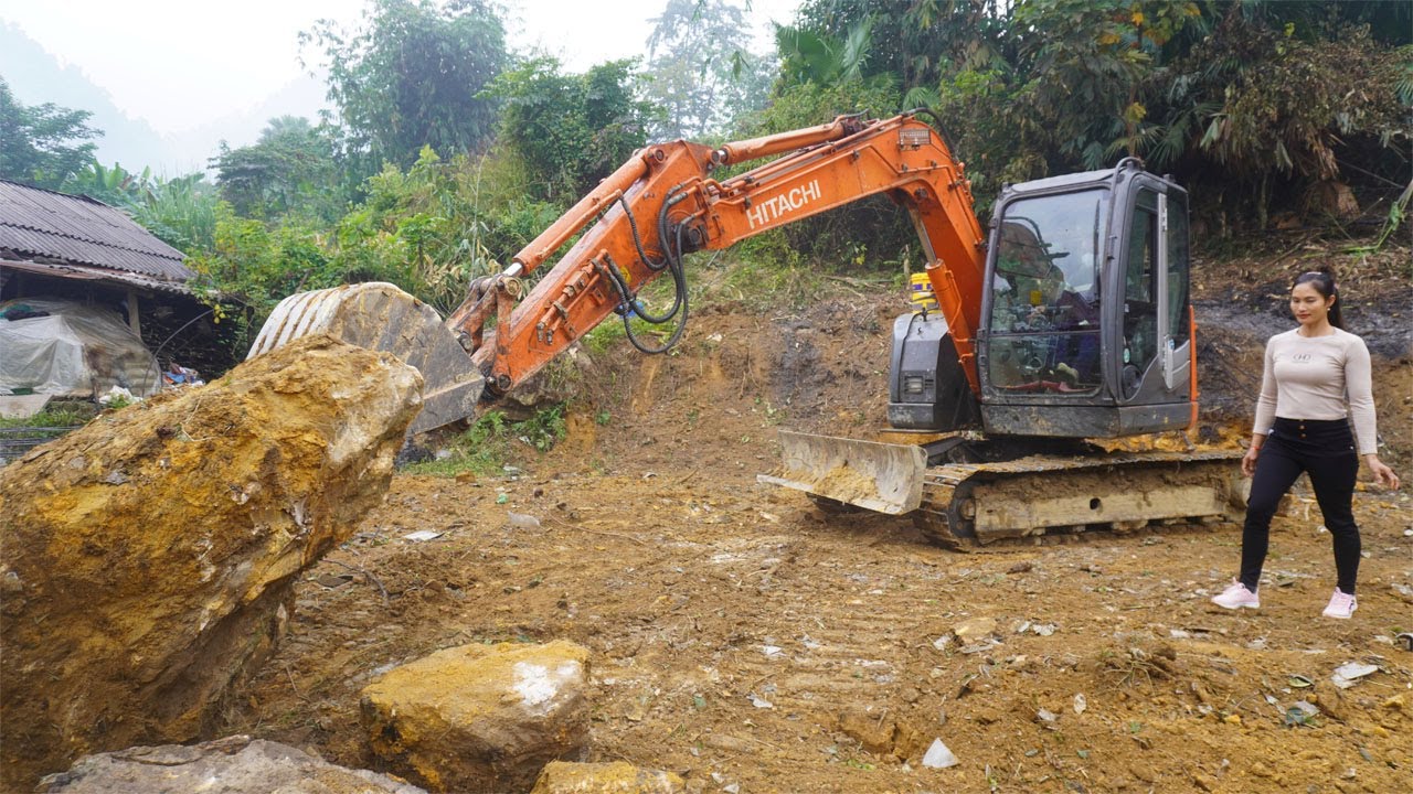 Excavator leveling the ground for building a new house - Girl leading excavator working