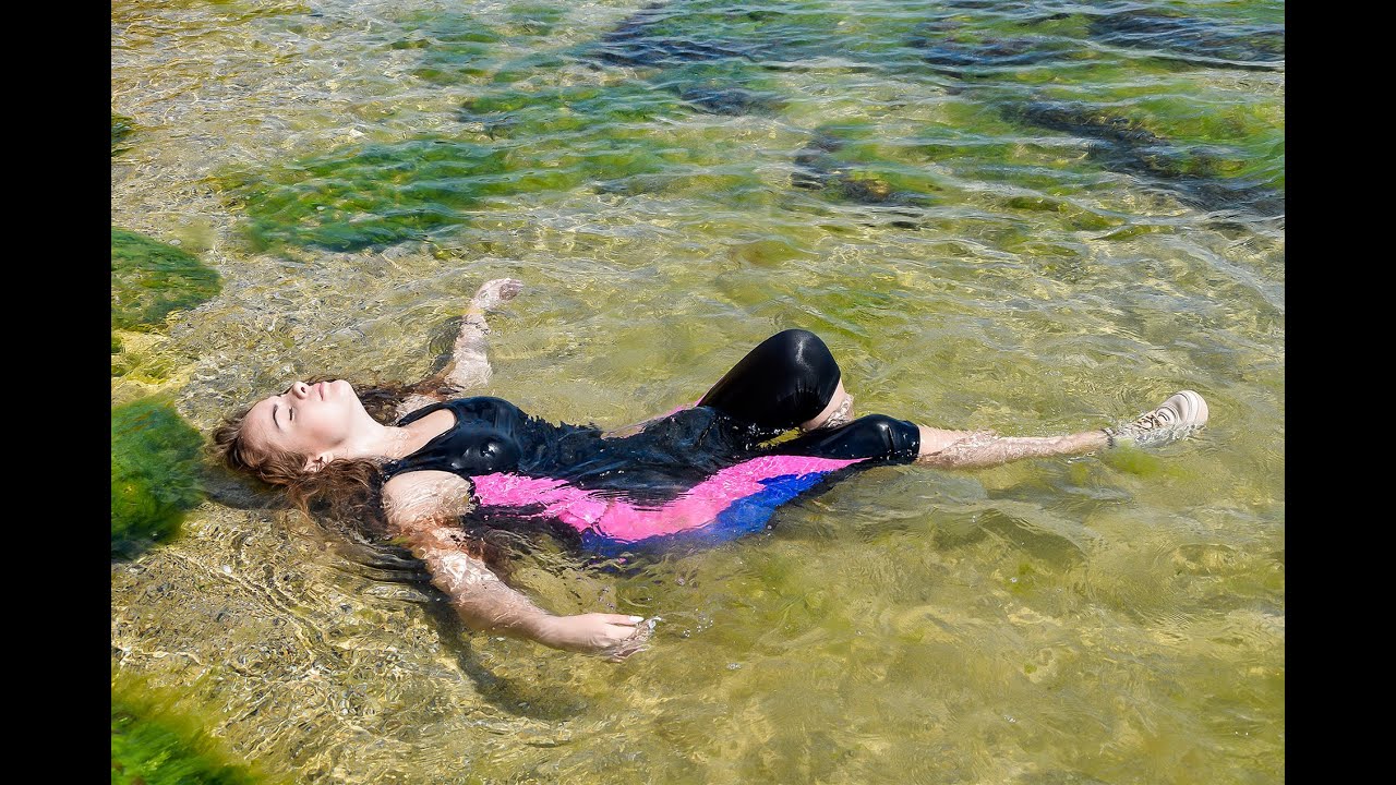 beautiful sportswoman poses cool in wet clothes on the beach by the sea for wetlook video