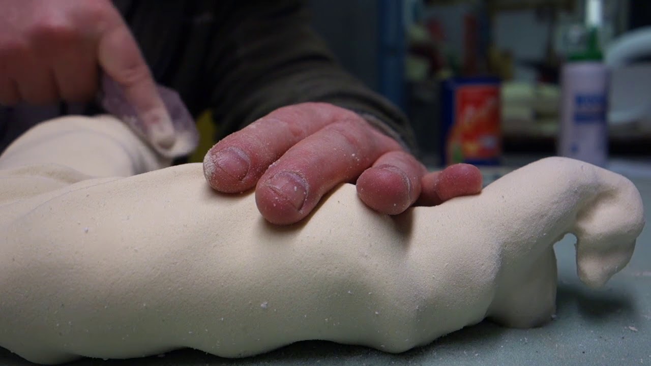 Sanding and sculpting a polyurethane foam arm.