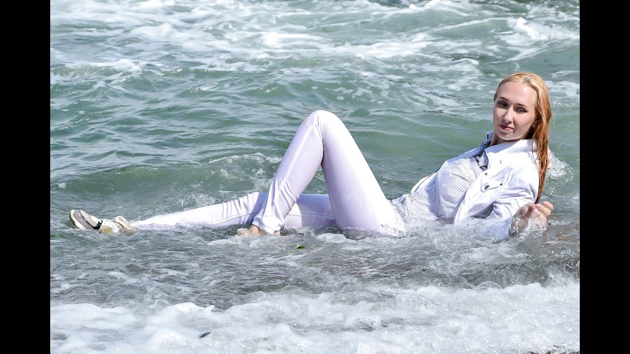cute girl in wet white clothes poses great on the beach by the sea for wetlook video