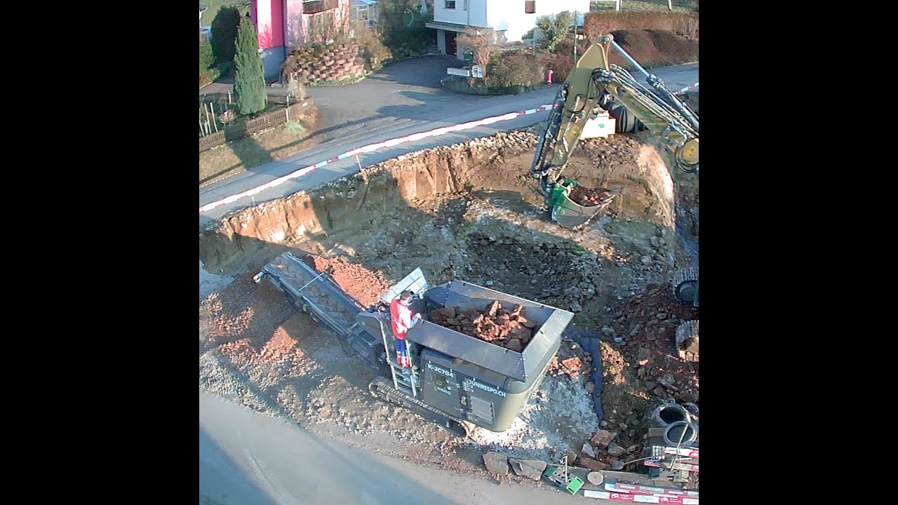 Grosser Kettenbagger beschickt 12t Brecher von Aushub