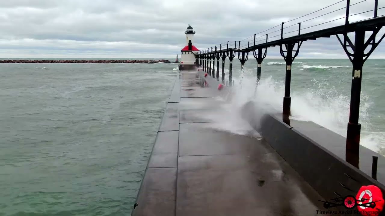 Woman Hanging On To Michigan City Lighthouse & Pier As Monster Waves Crash Over It 4K Drone Footage