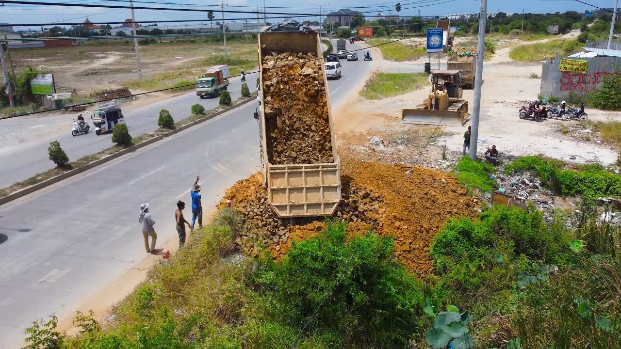 First Starting Open New Project Processing By Heavy DumpTruck With Bulldozer Push Stone into Water