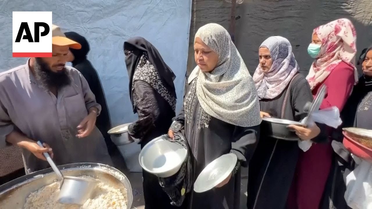 Dozens of Palestinians line up to get rice from a charity kitchen in Gaza