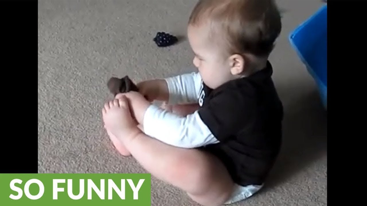 Frustrated baby can't put his sock on