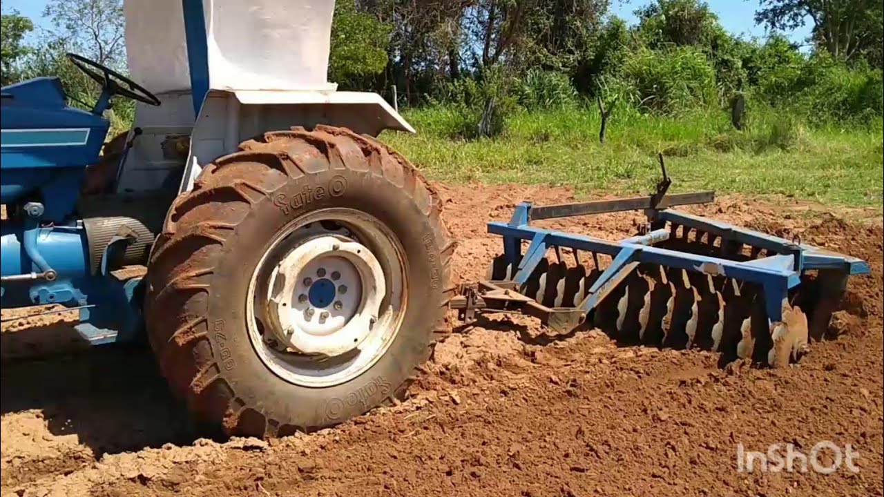 Trator Ford 5610 gradeando terra com a tatu 28 discos