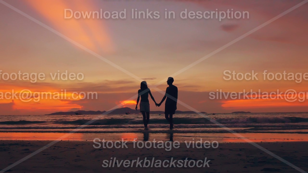 Slow motion silhouette of happy loving couple walk at beach on sunset in ocean shore