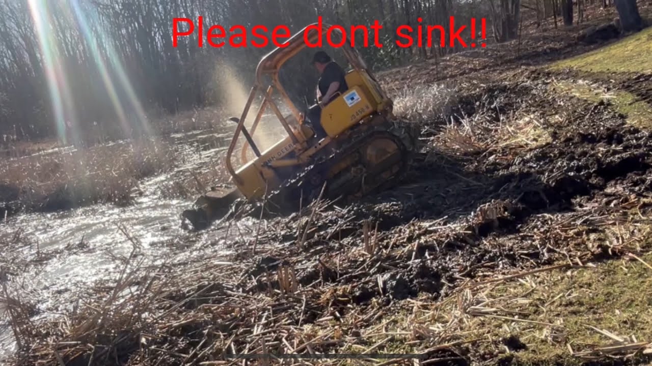 Bulldozer cleaning out a pond and saving old tractor