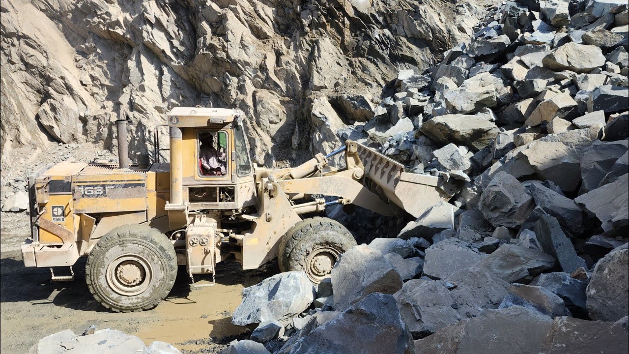 Powerful Loading Machine in Action: Caterpillar 966E Loading Rocks into Tractor Trolleys