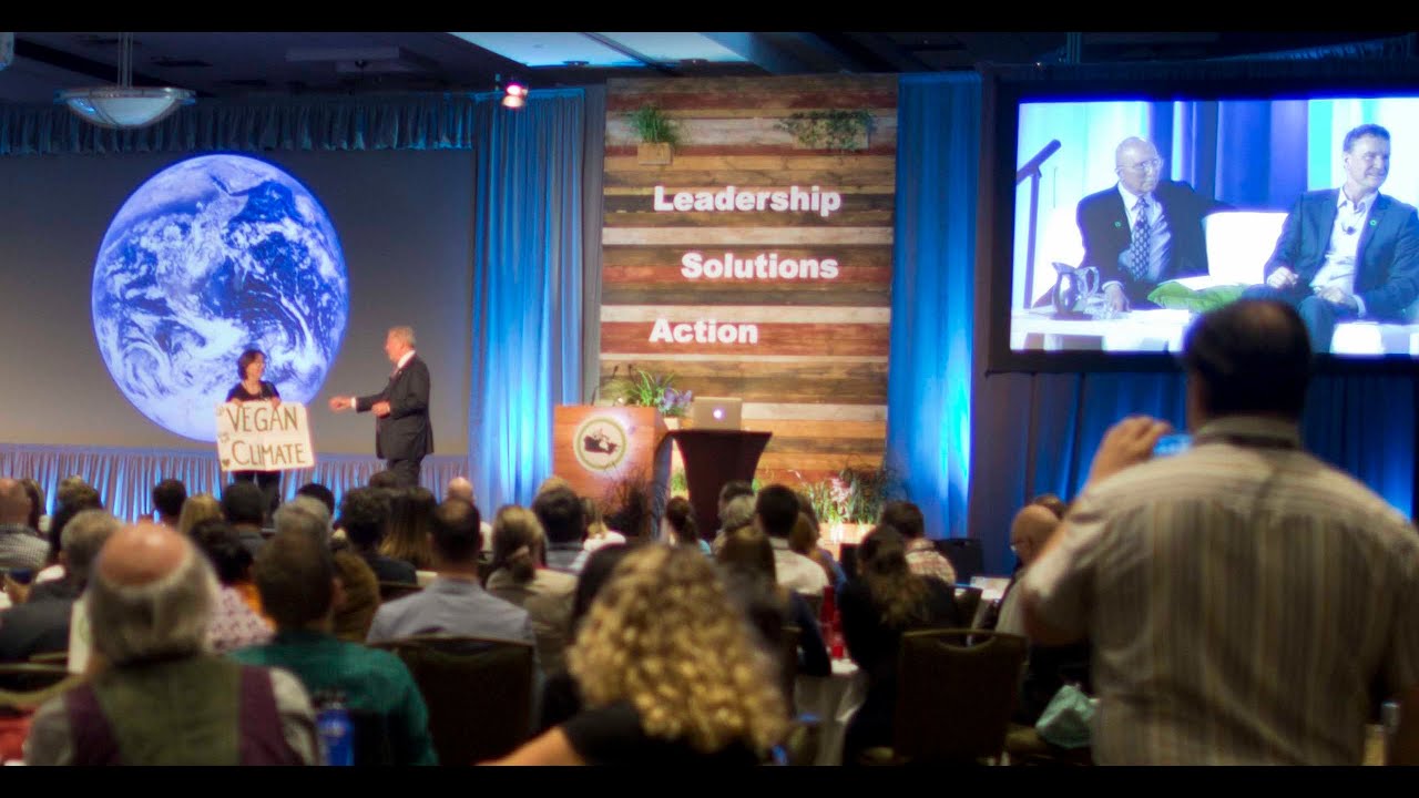 Activist Jenny jumps on stage at Al Gore climate training with the sign VEGAN for the CLIMATE