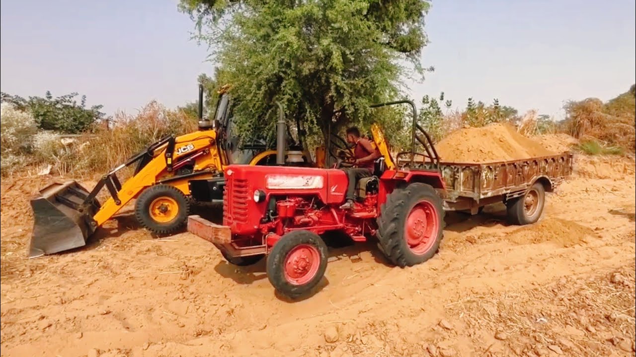 Load Red Soil into The Mahindra tractor using a JCB machine