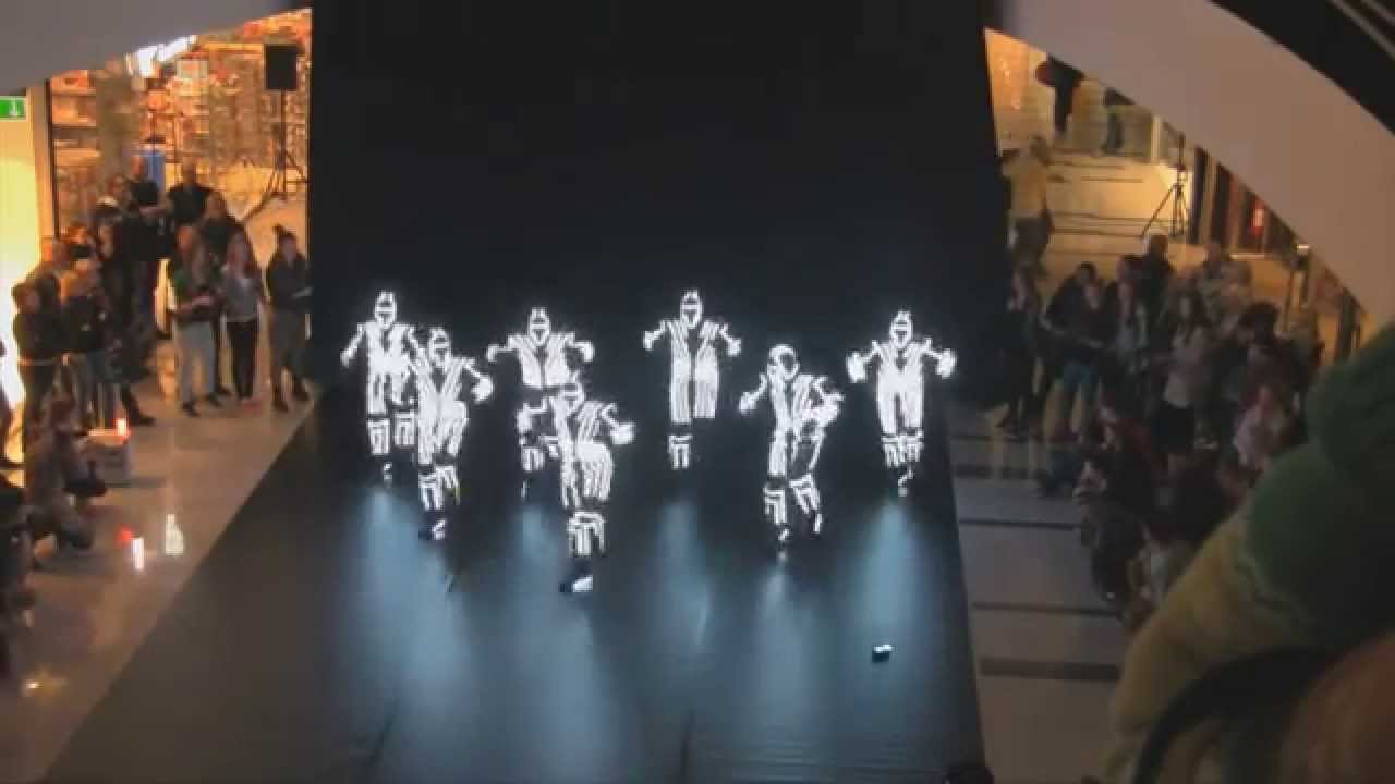 De repente começa uma atuação de dança com luzes no meio do shopping