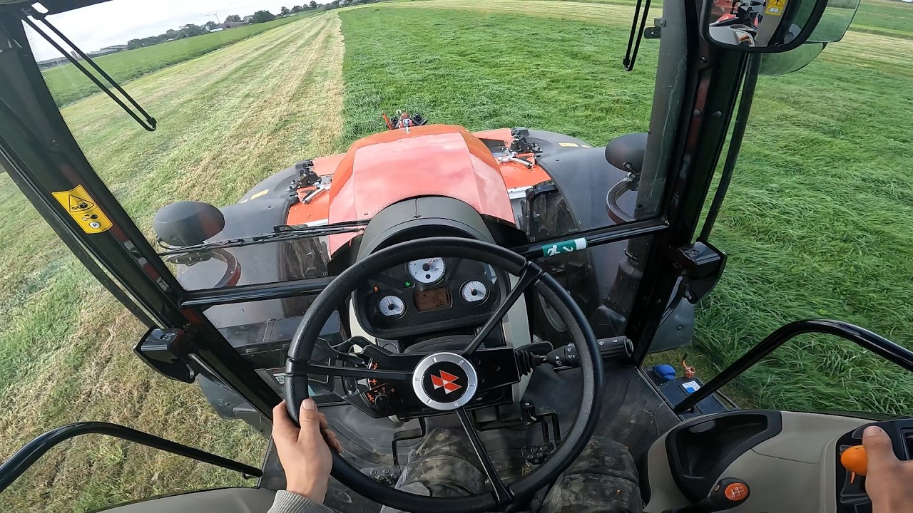 Вид из кабины Massey Ferguson 4710M, скашивающего свежую траву с помощью силосного прицепа