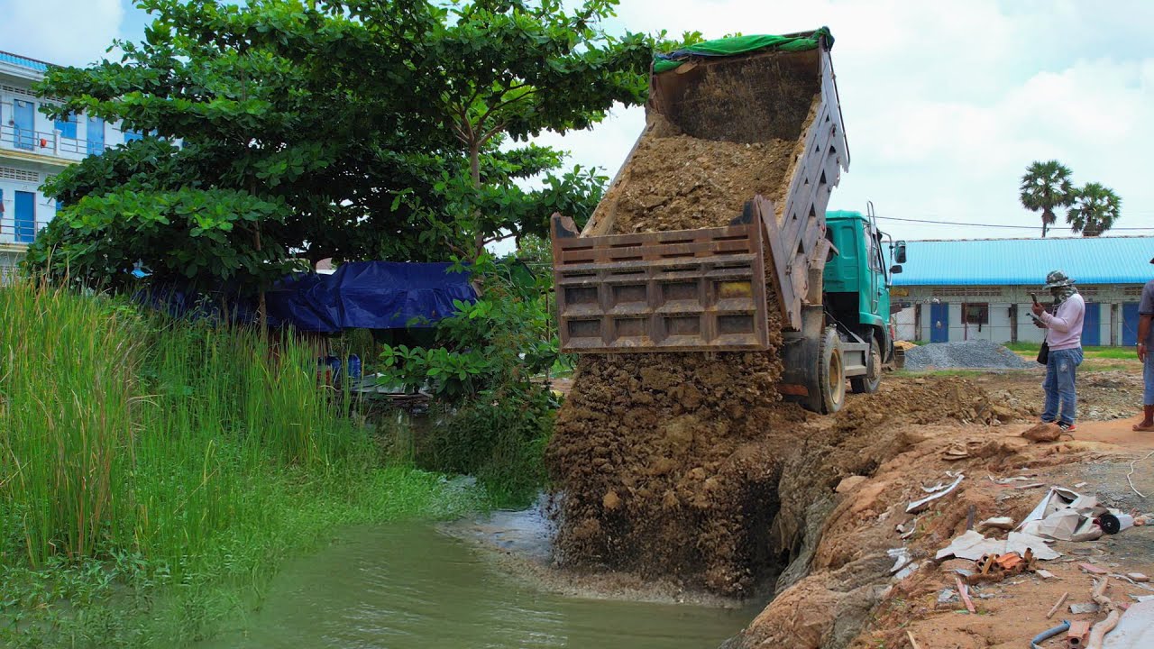 Earthworks: Dump Truck Loads of Dirt Reshaping the Landscape by the Pushing Soil into a deep water