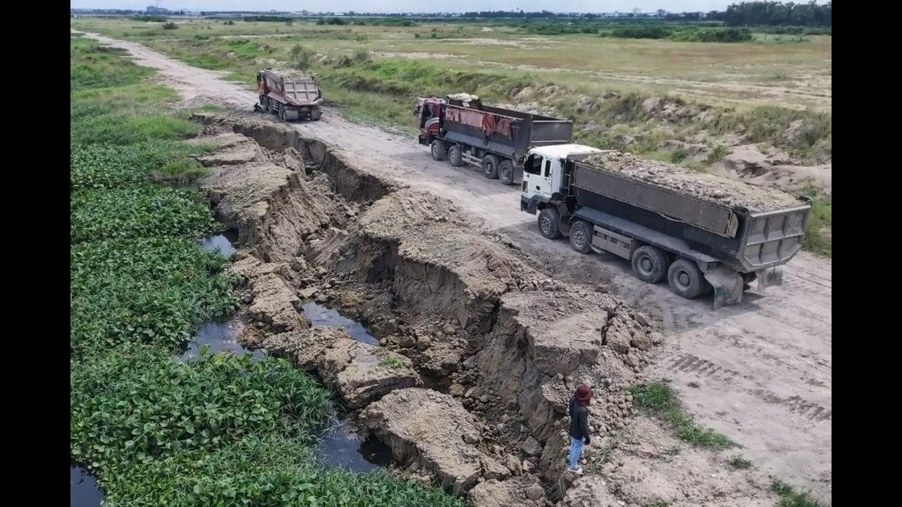 Dump Trucks Unloading Soil Filling Big Lake With Komatsu Bulldozer