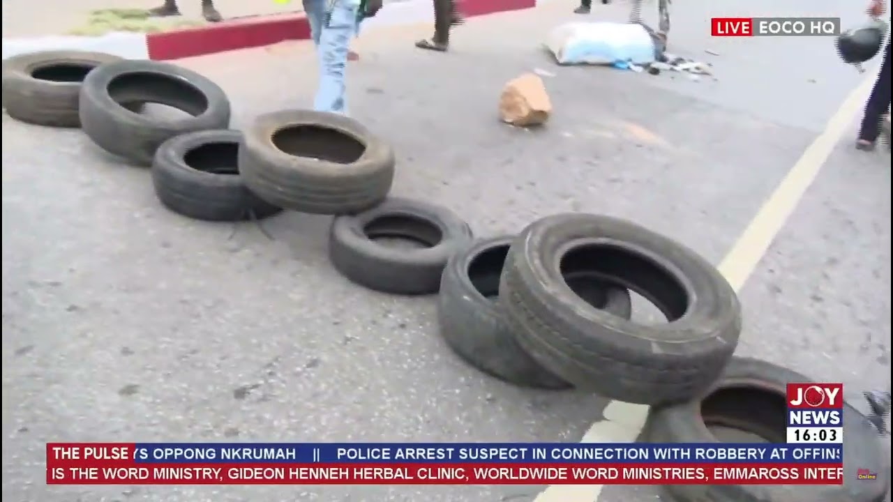 NPP supporters block the road with car tyres to prevent police riot vehicle from moving