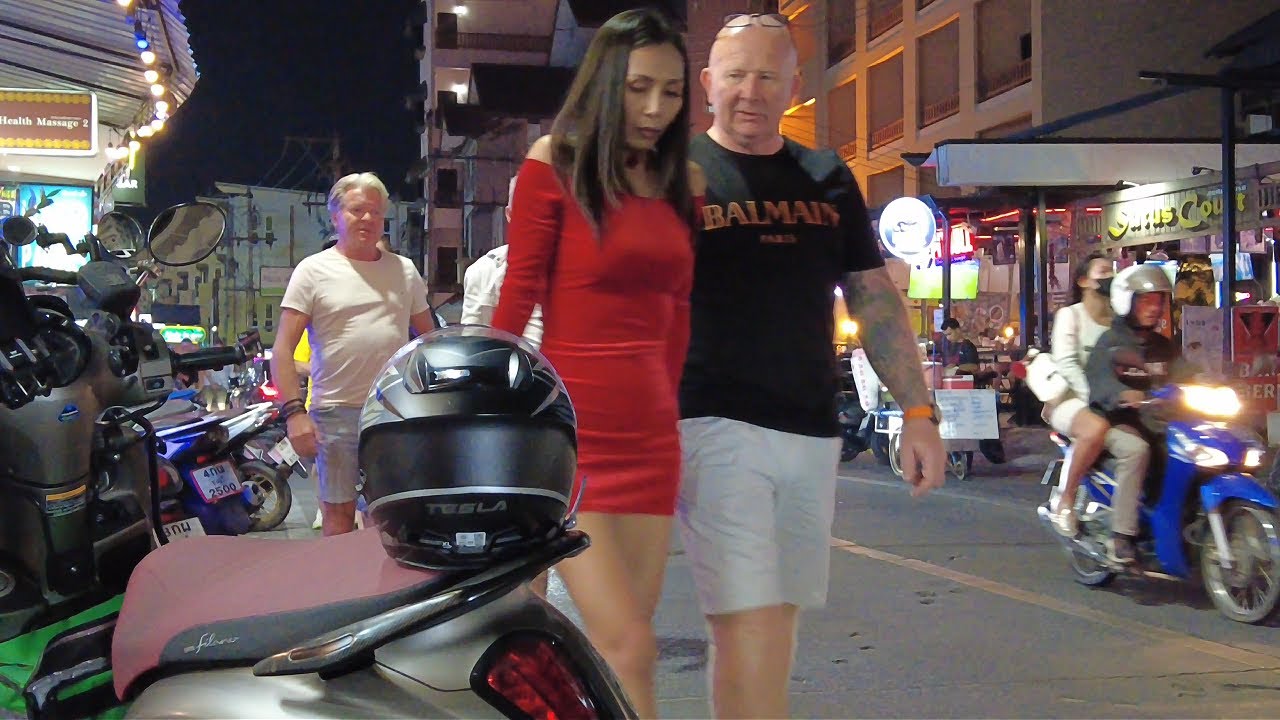 Пожилой белый мужчина с нежностью посмотрел на молодую тайскую женщину. Ночные уличные сцены Паттайи