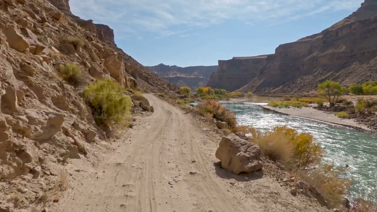 Stock Video - POV driving on dirt road along the Green River on sunny day