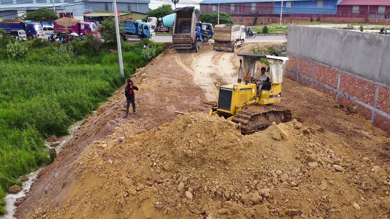 Niesamowita spycharka KOMATSU D31P spychająca ziemię 5-tonowymi wywrotkami 
