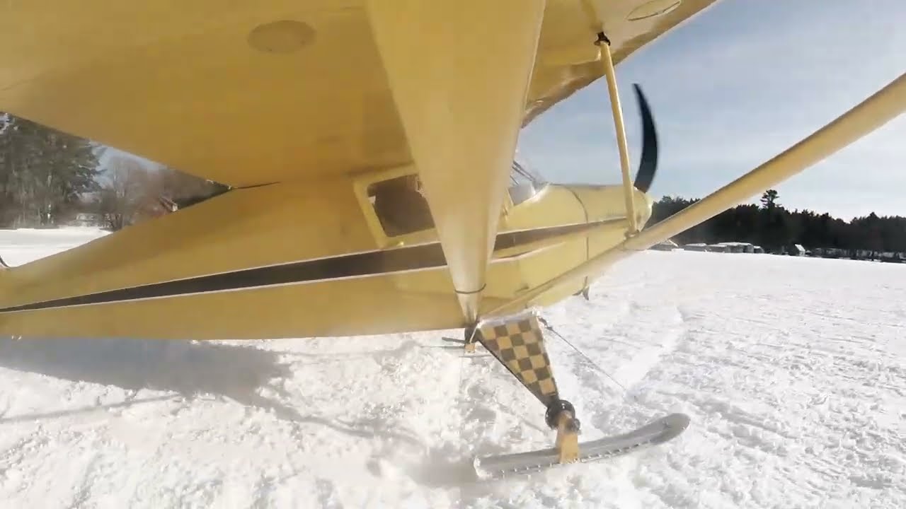 65 H.P.  Taylorcraft on skis taking off from snow.