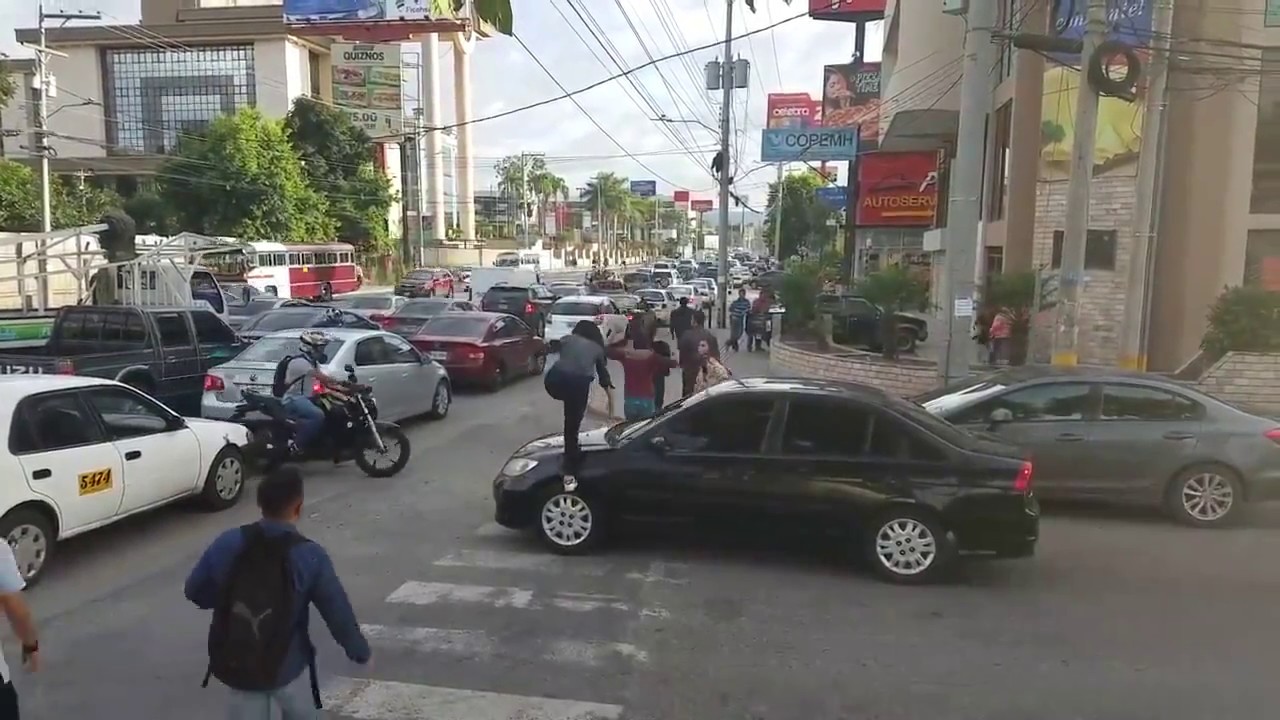 Pedestrians walk over a front car hood that stop in the pedestrian lane
