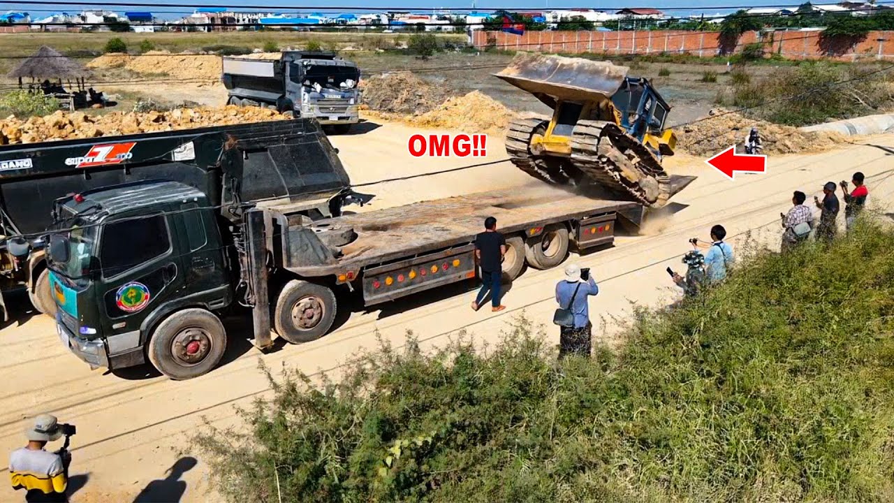 Nice new project with bulldozer Komatsu D40P filling up land with soil and dump trucks 