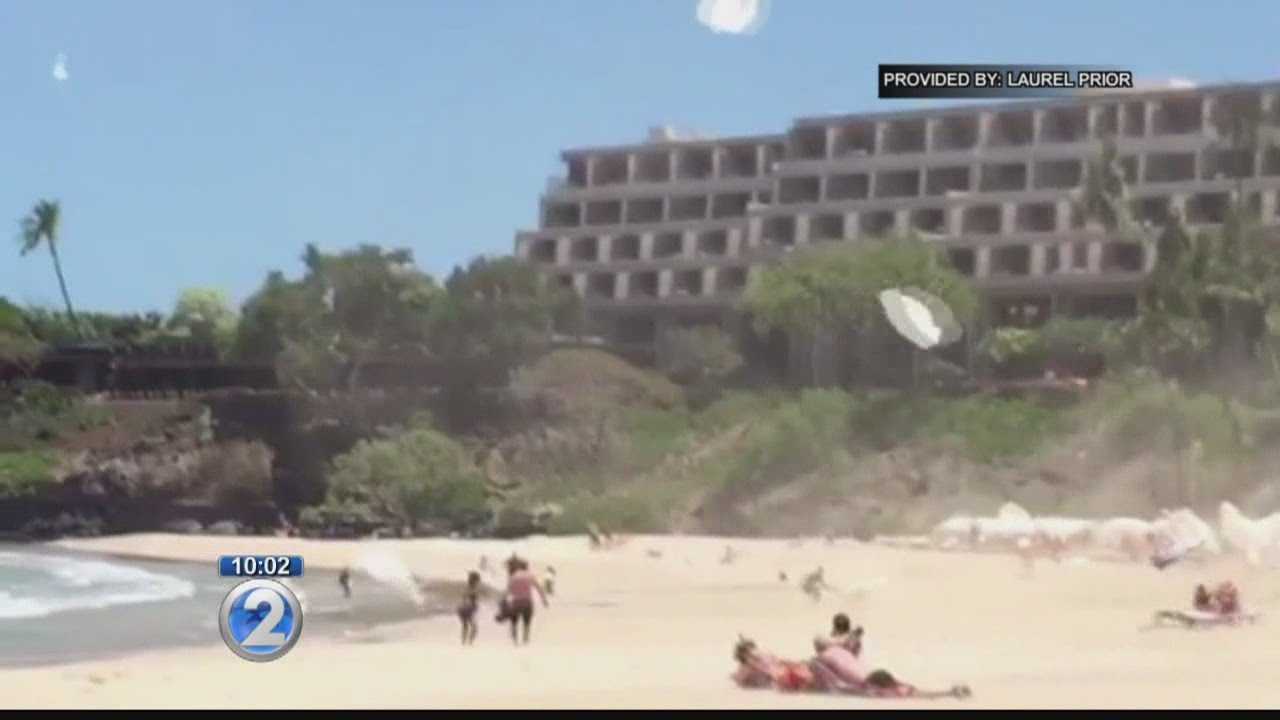 Sand devil caught on camera hurling umbrellas around beachgoers