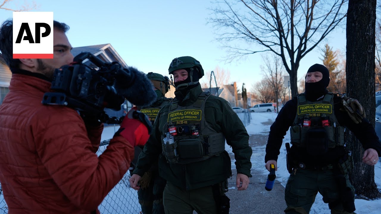 AP reporters pushed back to their car by federal officers while documenting operation