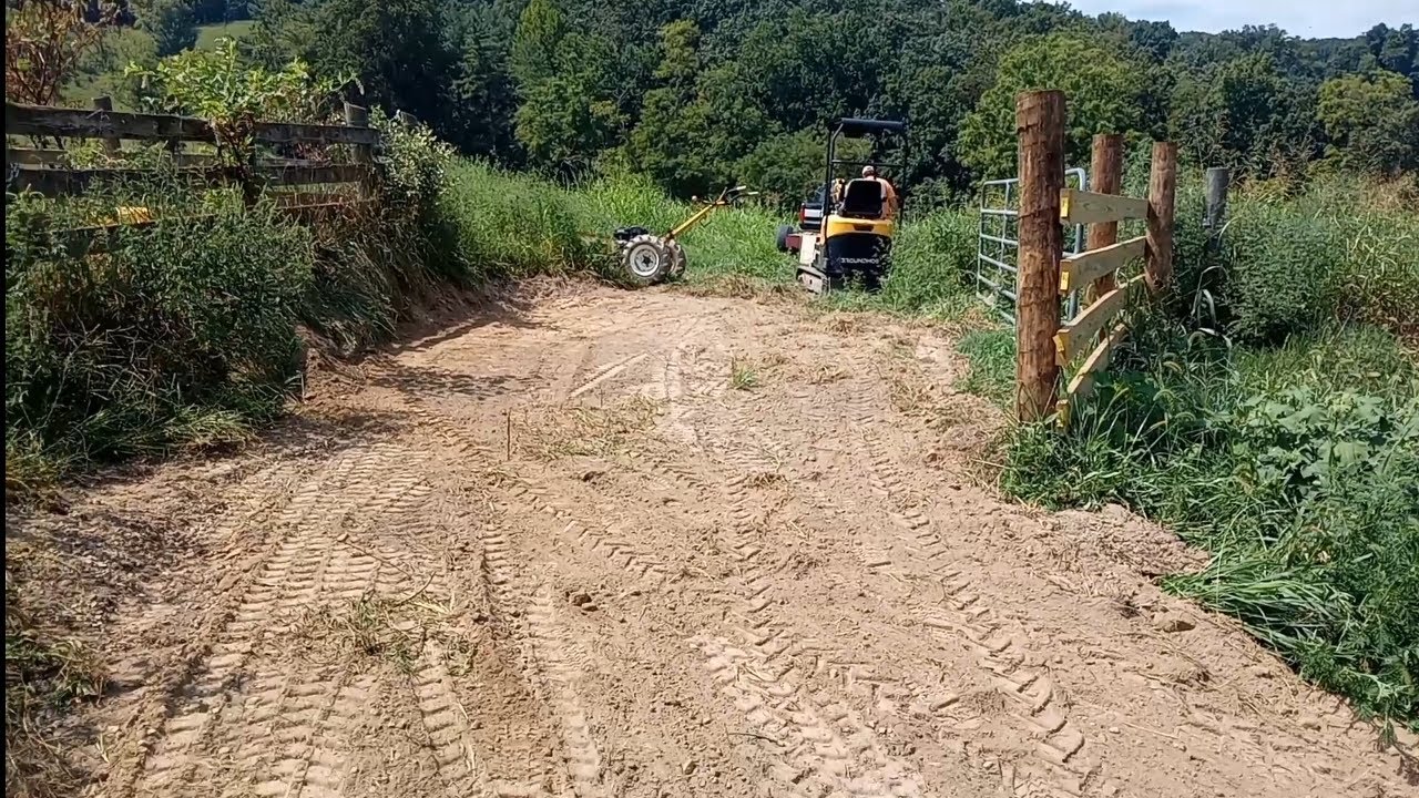 Groundhog fixing another farm road  and aborting steep hill side 