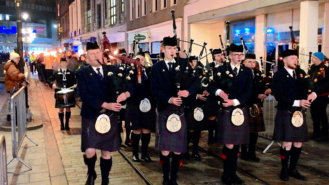 Dundee Hooley St Andrews Day torchlight parade with Dundee Pipe Band marching through City streets
