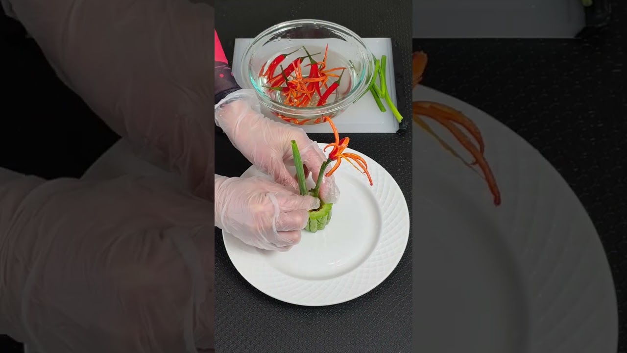 小米辣雕成盛开的花朵，红艳灵动，苦瓜化作清雅的花瓶，翠绿通透，承载着自然的清新与平衡