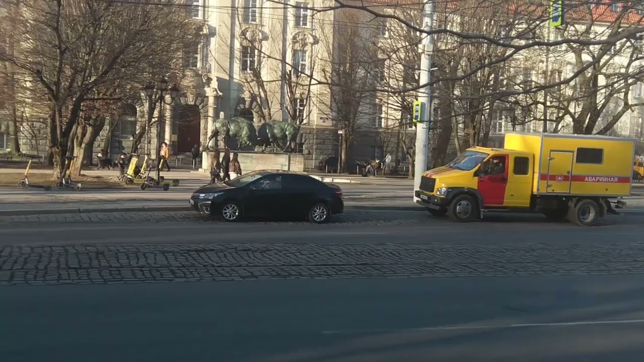Tourists walking in the center take photos near the sculpture with bulls