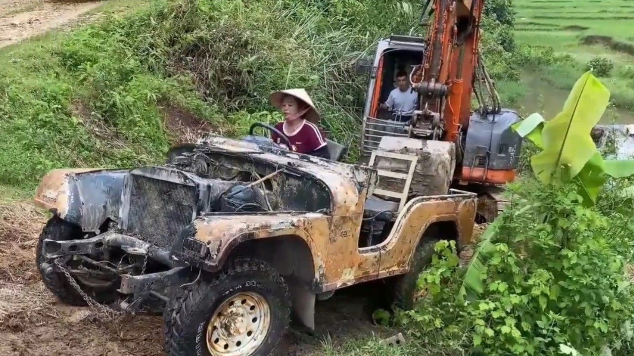Rescue and repair operation using excavator to recover abandoned jeep from canal