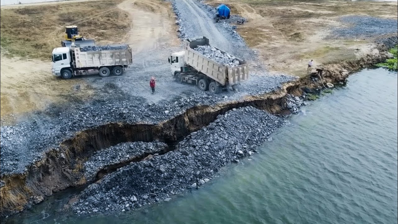 Dump Trucks Loading Stones Fill The Crack With Sink Land, Dozer Pushing Stones