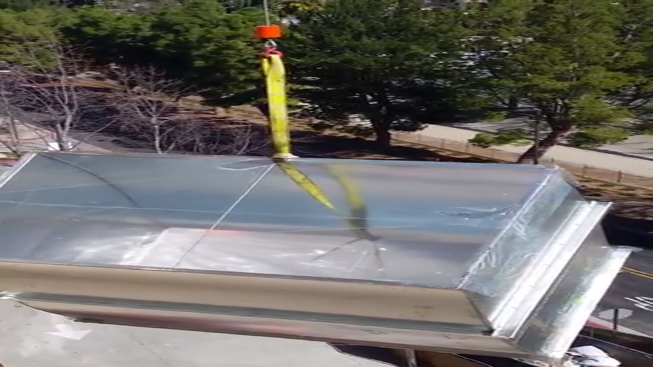 Small Footprint Crane lifting HVAC equipment up the side of a building