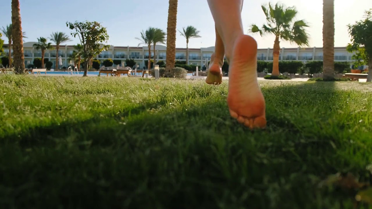 close up of young girl legs running barefoot on the green grass slow