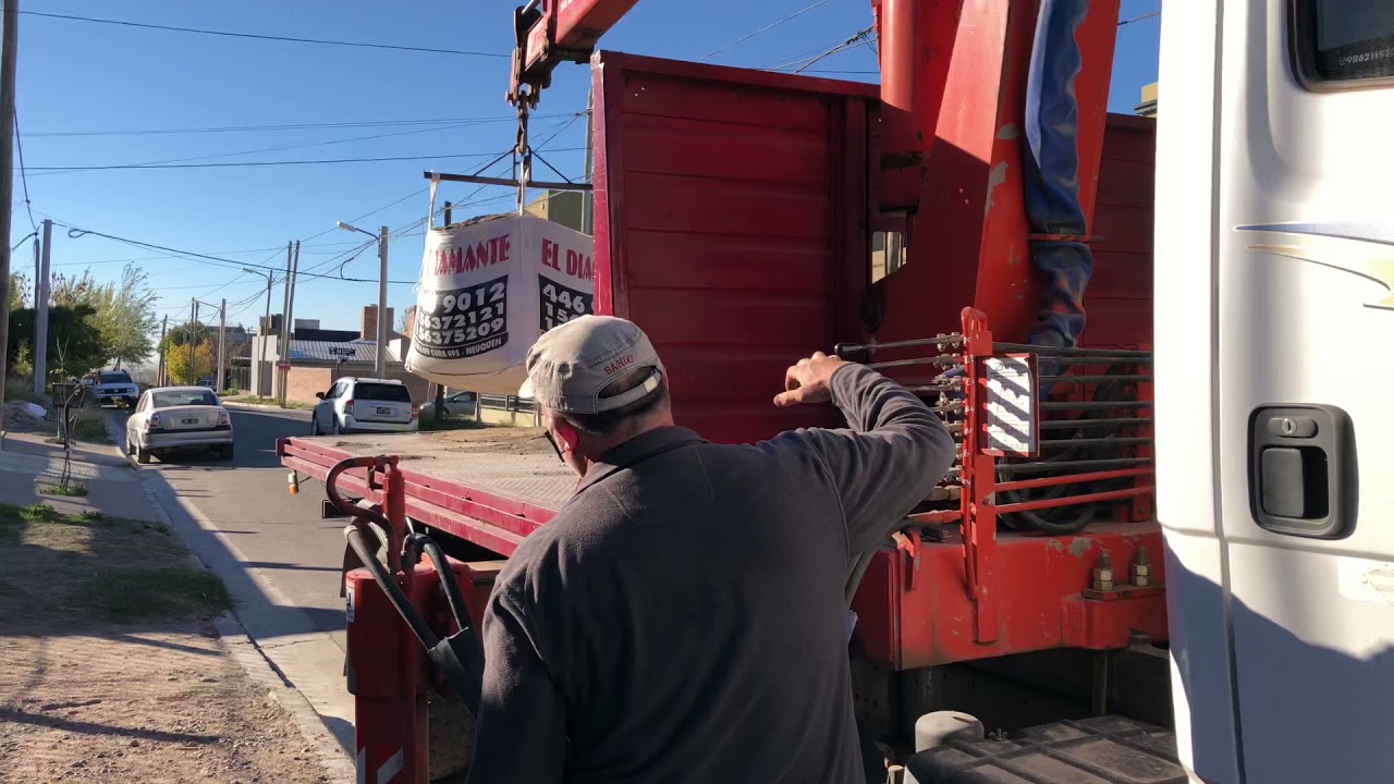 Descargando del camión y depositando bolsón de arena para la obra de construcción
